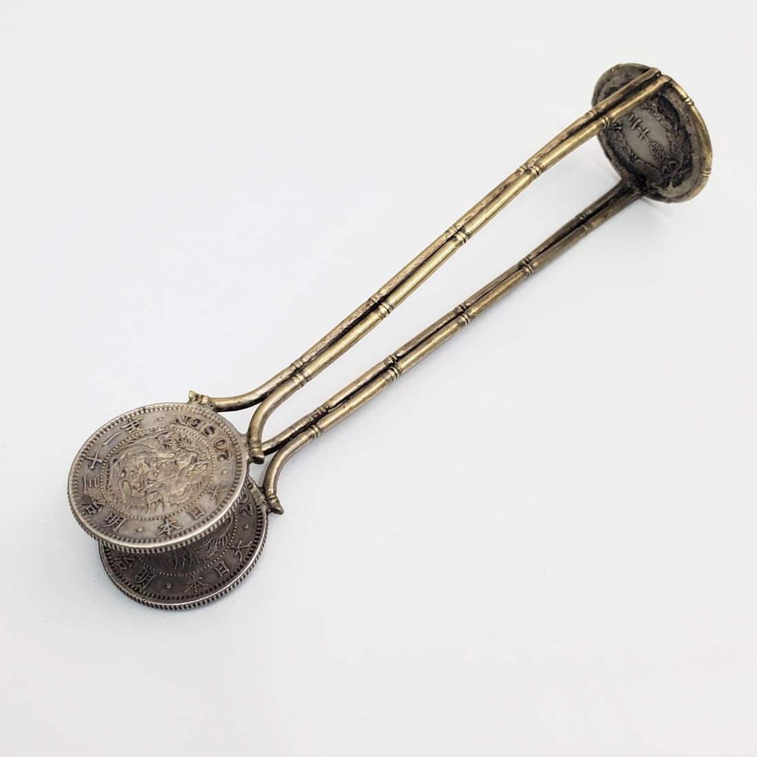 Metal Sugar Tong Made From Japanese Meiji Coins: Metal Sugar Tong Made From Japanese Meiji Coins. Condition: Generally Very Good. Dimensions: L- 4.5" x W-1". Provenance: From a Long Island, NY Home. Please note the absence of a Condition Report does