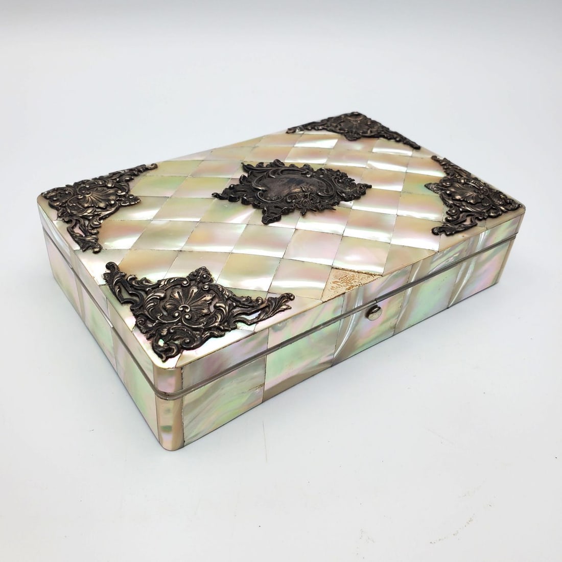 Antique English Silver Mounted Mother of Pearl Box: Antique English Silver Mounted Mother of Pearl Cigar Box. Silver is Fully Marked. Condition: Generally Good. Silver is Tarnished & Cover is Missing a Tile. Dimensions: L-6" x W-4" x H-1.5". Provenance