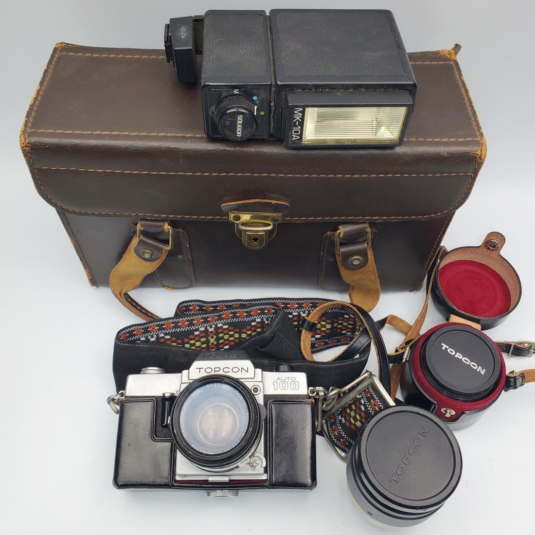 Vintage Beseler Topcon Auto 100 35mm SLR Camera: Vintage Beseler Topcon Auto 100 35mm SLR Camera In Leather Case Along w/ 2 Tokyo Kogaku Japan UV Topcon Lenses, & 1 Soligor MK - 10A Electronic Flash Unit. Condition: Generally Good. One Strap of Case