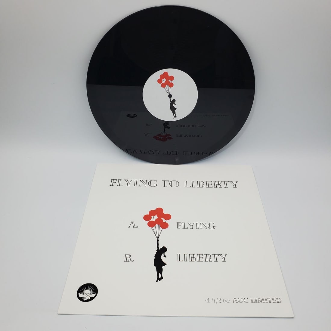 After Banksy "Flying to Liberty" Vinyl 14/100: After Banksy, Vinyl EP Record "Flying to Liberty". Red Version. Hand Numbered 14/100 in Black Pen. In Original Cover & Plastic. We Do Not Guarantee the Authenticity of This Item. Condition: Excellent.
