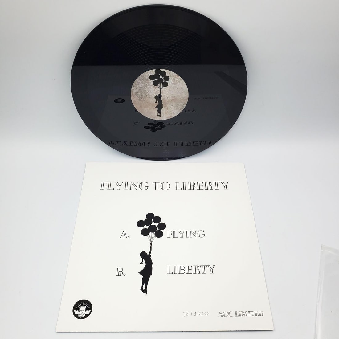 After Banksy "Flying to Liberty" Vinyl 12/100: After Banksy, Vinyl EP Record "Flying to Liberty". Black & White Version. Hand Numbered 12/100 in Black Pen. In Original Cover & Plastic. We Do Not Guarantee the Authenticity of This Item. Condition: