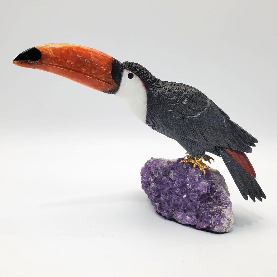 Vintage Carved Sculpture of a Toucan: Vintage Carved Sculpture of a Toucan Made From Various Gemstones Such As Black Obsidian, Orange Calcite & Mounted on a Amethyst Base. Condition:Dimensions: L- 8.5" x W- 4.5" x H- 4.25". Provenance: Fr