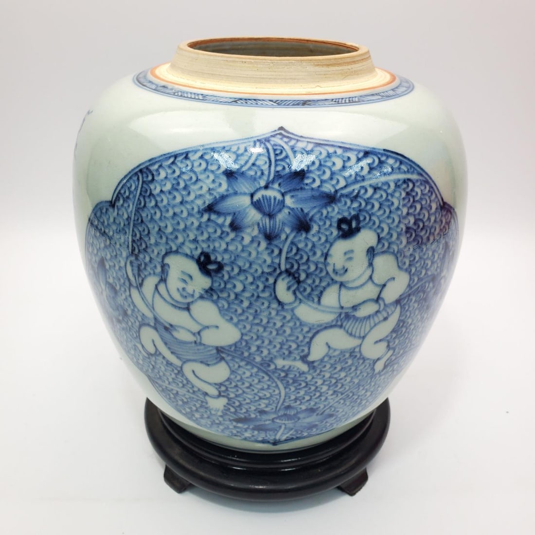 Chinese Blue & White Porcelain Vase: Chinese Blue & White Porcelain Vase Depicting Babies. With Wooden Base. Condition: Generally Good. Sold As Is. Missing a Cover. Dimensions: H- 8.75" x Dia- 8.5". Provenance: From a Long Island, NY Hom