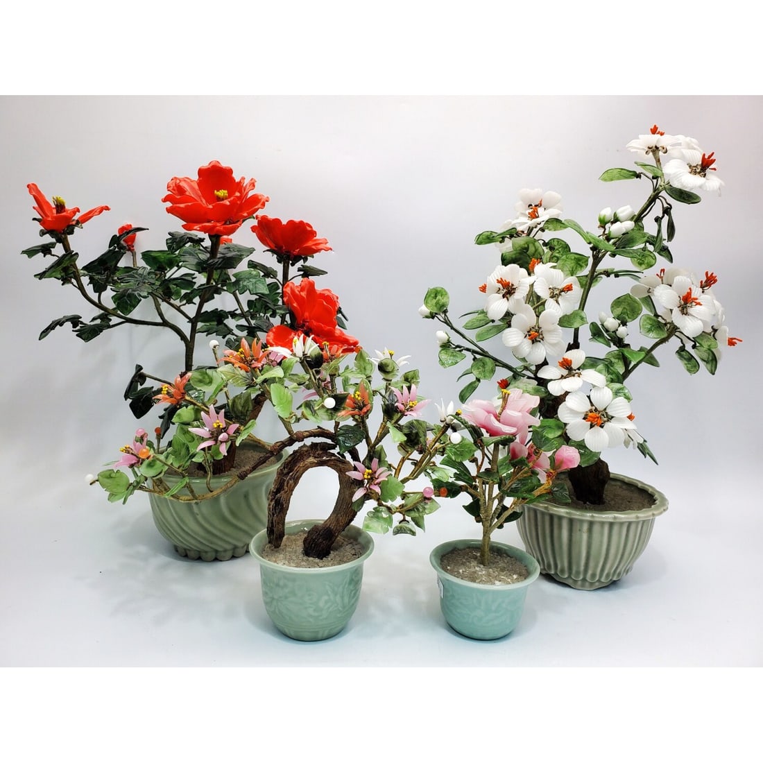 Lot of 4 Chinese Carved Stone Bonsai Tree Figures: Lot of 4 Chinese Carved Stone Bonsai Tree Figures on Porcelain Bases. Condition: Generally Good. There Are Some Broken Flowers & Leaves. Dimensions: Largest-H-16" x Dia-11". Provenance: From a Long Is