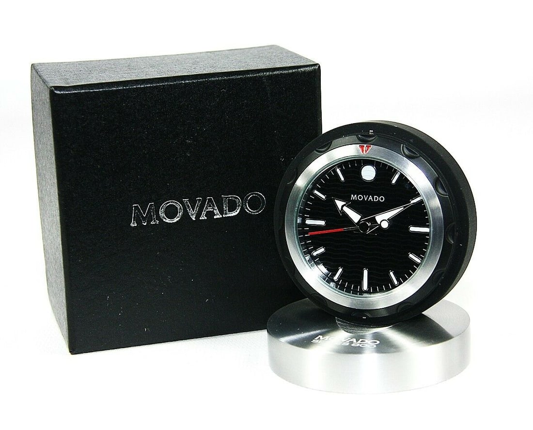 MOVADO MUSEUM DIAL SLEEK AND VERSATILE TRAVEL ALARM CLOCK: MOVADO"CAN" CLOCKTRAVEL ALARM CLOCKBRAND NEW IN ORIGINAL MOVADO BLACK BOXWith ORIGINAL Foam InsertsMODEL: RBL000218M2 1/2" DIAMETER x 1" THICK (closed in the "can")3/4" THICK (opened)Battery in the pi