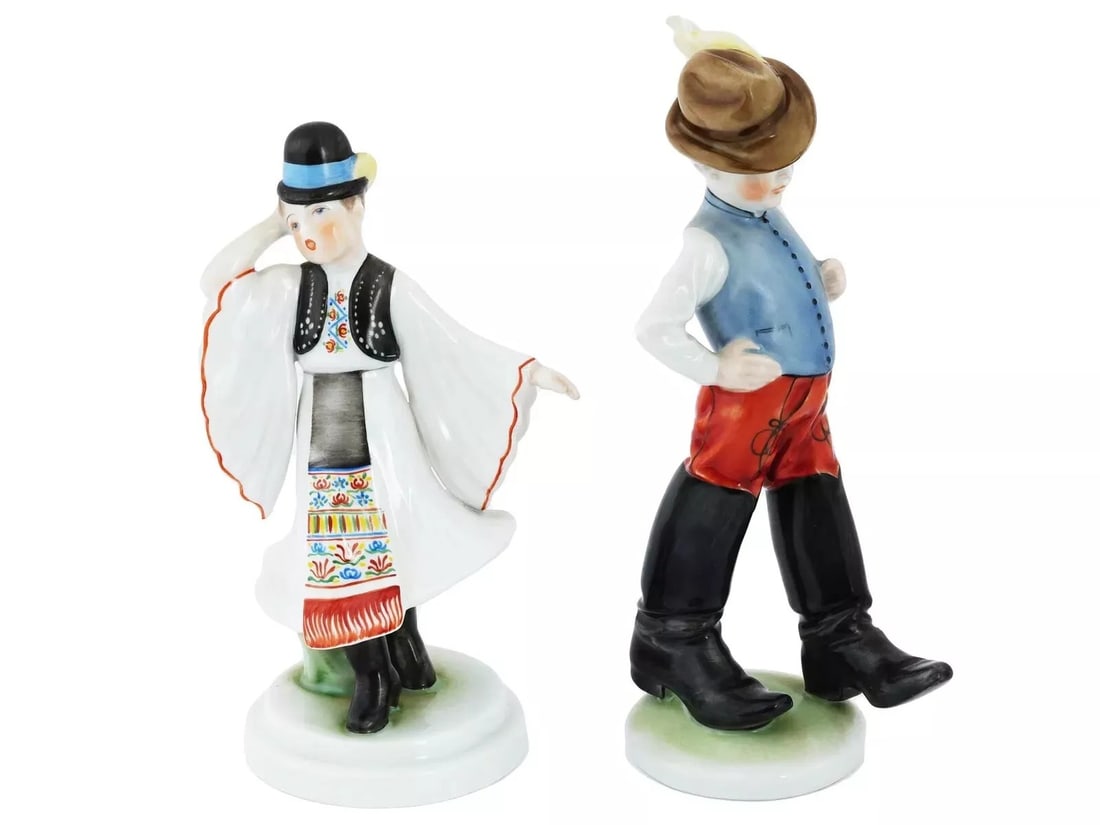Vintage 1960s HEREND PORCELAIN HANDPAINTED YOUNG LADY AND BOY FIGURINES, 8 1/2": A pair of mid-20th century hand-painted porcelain figurines by Herend, a Hungarian porcelain manufacture active since 1839. Ca. 1960s. First. A boy in traditional Hungarian costume with big boots. Mod