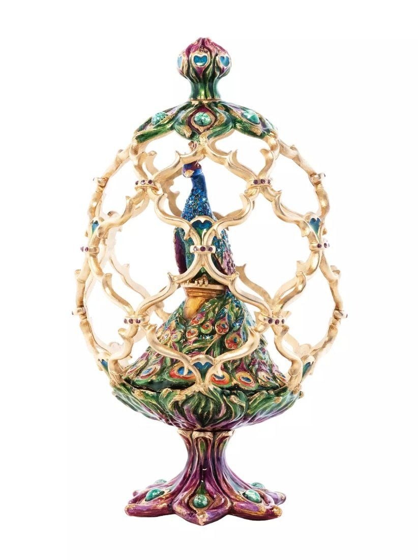 JAY STRONGWATER ROMAN PEACOCK EGG OBJET FIGURINE: JAY STRONGWATERROMAN PEACOCK EGG OBJETPeering out from his perch within a cage of delicate golden filigree, A majestic peacock proudly displays his cascade of colorful plumage. Crafted in incredible d