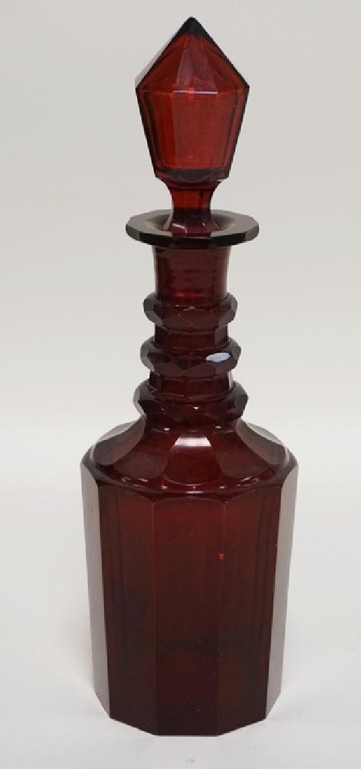 RUBY CASED CUT GLASS DECANTER WITH A HOLLOW BLOWN AND: RUBY CASED CUT GLASS DECANTER WITH A HOLLOW BLOWN AND CUT STOPPER. 13 INCHES HIGH. HAS A FEW VERY SMALL NICKS.