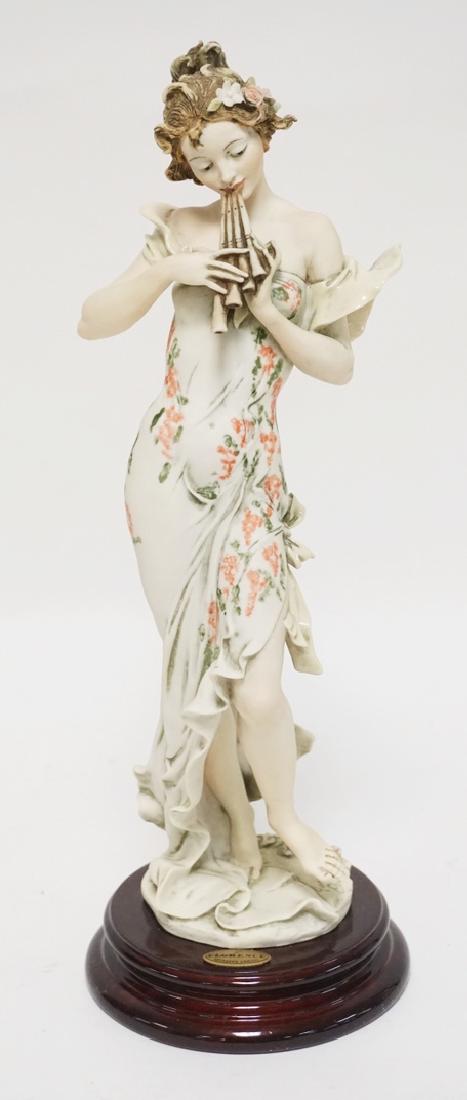 GIUSEPPE ARMANI SCULPTURE OF A WOMAN IN A FLORAL DRESS: GIUSEPPE ARMANI SCULPTURE OF A WOMAN IN A FLORAL DRESS PLAYING A PAN FLUTE. 14 1/2 INCHES HIGH.