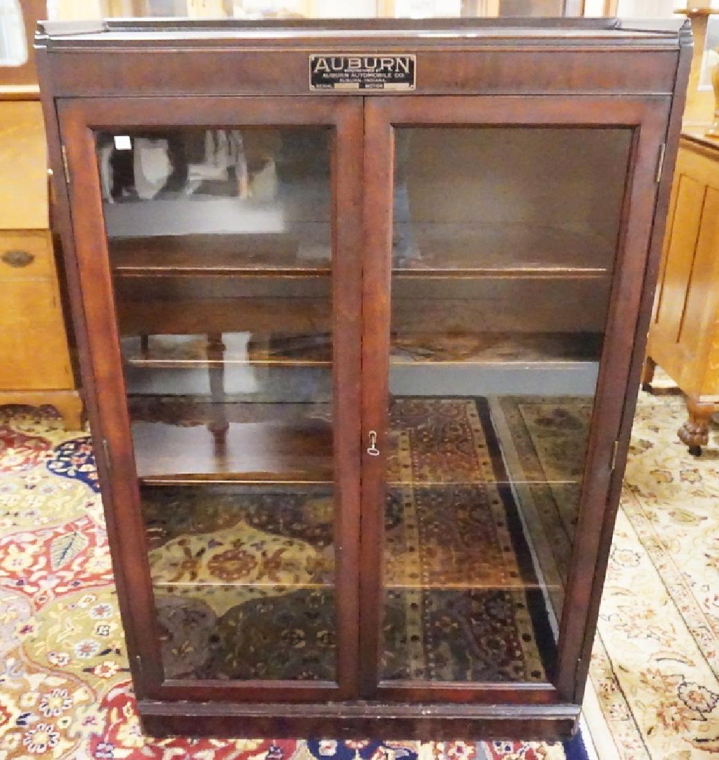 MAHOGANY BOOKCASE WITH GLASS DOORS. AUBURN AUTOMOBILE: MAHOGANY BOOKCASE WITH GLASS DOORS. AUBURN AUTOMOBILE COMPANY TAG AFFIXED TO THE TOP. 35 INCHES WIDE. 51 3/4 INCHES HIGH.