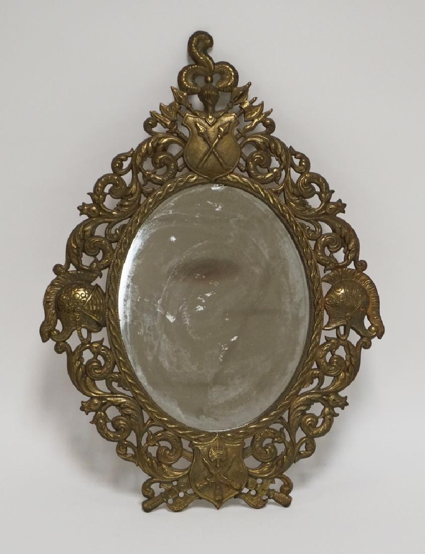 BRASS FRAMED MIRROR WITH AN OPENWORK BORDER DEPICTING: BRASS FRAMED MIRROR WITH AN OPENWORK BORDER DEPICTING ARMS AND ARMOR. 17 1/2 X 12 1/2 INCHES.