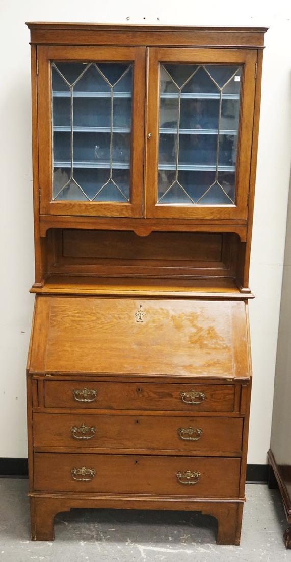 OAK DESK: OAK DESK WITH A BOOKCASE TOP HAVING LEADED GLASS DOORS. 79 1/2 INCHES HIGH. 36 INCHES WIDE.