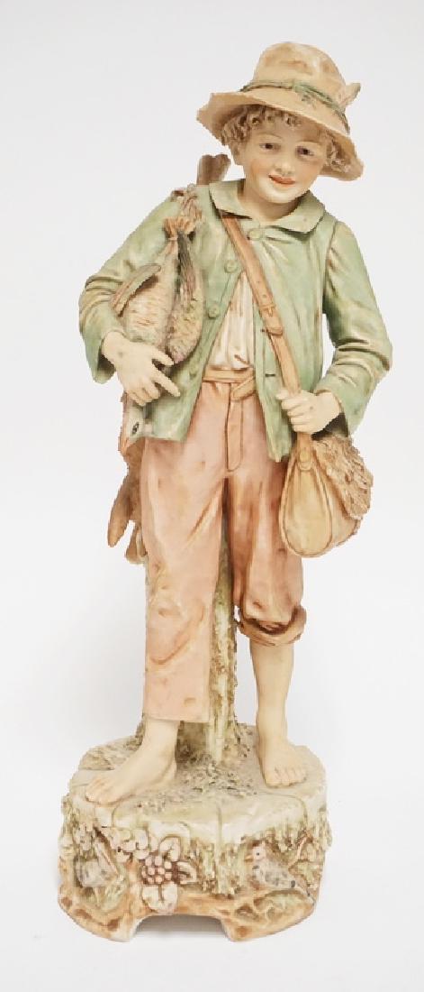 ROYAL DUX: ROYAL DUX PORCELAIN FIGURE OF A BOY CARRYING FISH AND A CREEL. 15 3/4 INCHES HIGH. SMALL NICKS TO HAT.