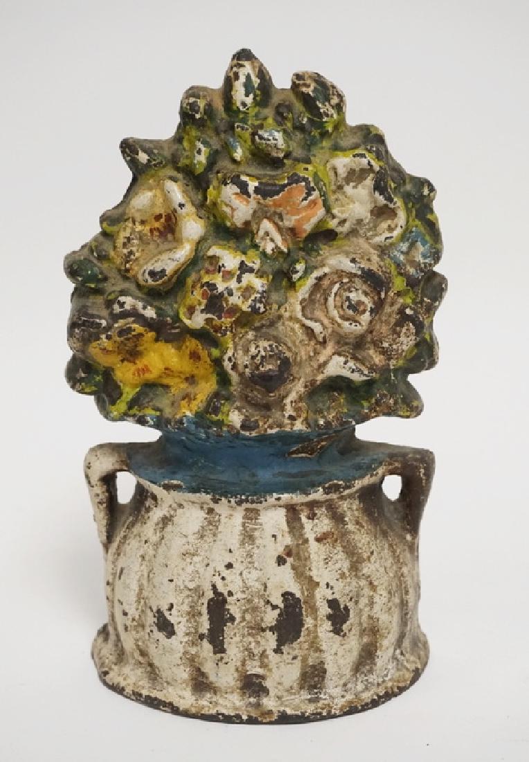 IRON FLOWER DOORSTOP: ANTIQUE IRON DOORSTOP IN THE FORM OF A FLOWERING URN. 8 INCHES HIGH.