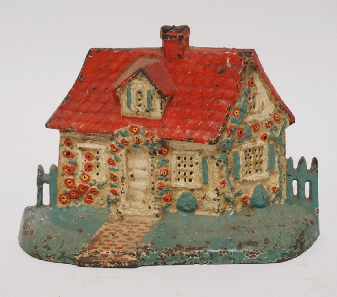IRON DOORSTOP: ANTIQUE CAST IRON COTTAGE DOORSTOP. 5 1/4 INCHES HIGH.