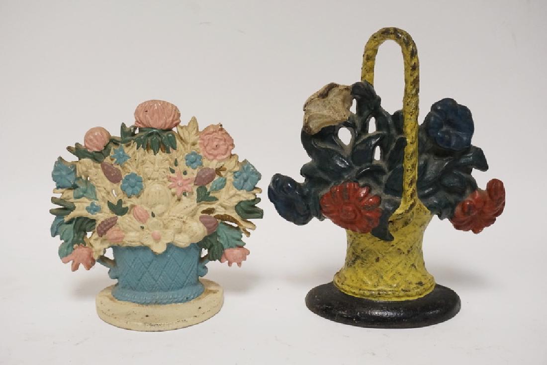 IRON FLOWER DOORSTOPS: LOT OF 2 CAST IRON FLOWER BASKET DOORSTOPS. TALLEST IS 9 1/2 INCHES.