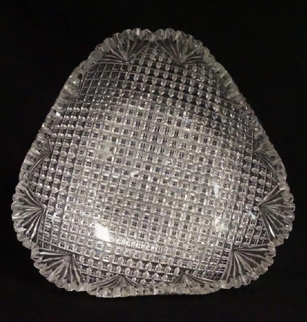 CUT GLASS: TRIANGULAR CUT GLASS BOWL. APPROX 9 INCHES WIDE. 2 1/2 INCHES HIGH. HAS A CHIPPED TOOTH AND A FEW WITH SMALL NICKS.