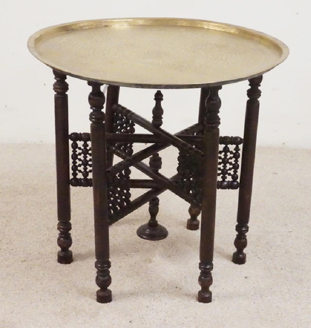MIDDLE EASTERN BRASS TRAY WITH CARVED BASE: MIDDLE EASTERN BRASS TRAY WITH AN ORNATELY CARVED WOODEN BASE. 25 INCH DIA. 24 INCHES HIGH.