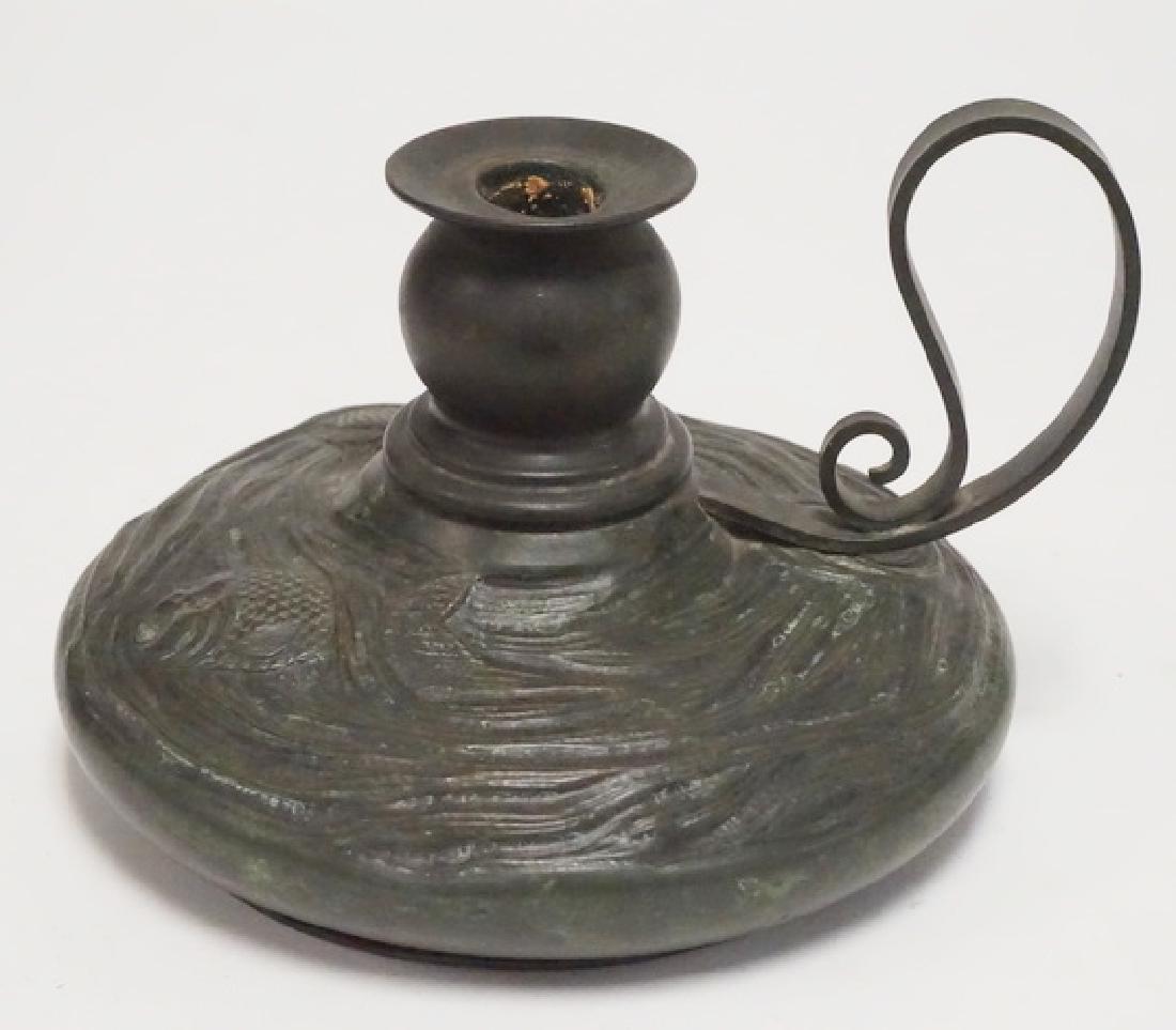 TIFFANY STUDIOS BRONZE CHAMBERSTICK: TIFFANY STUDIOS BRONZE CHAMBERSTICK WITH RELIEF DECORATION OF FIH AND SEAWEED. 7 1/2 INCH DIA. 5 INCHES HIGH. HAS SOME DENTING TO THE BASE.