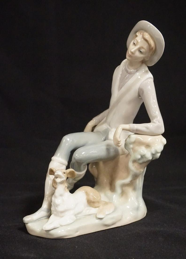 LLADRO: LLADRO PORCELAIN FIGURE OF A MAN SITTING ON A STUMP WITH HIS DOG AT HIS FEET. 7 3/4 INCHES HIGH.