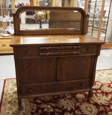 OAK SIDEBOARD: OAK SIDEBOARD WITH CARVED PAW FEET AND A MIRRORED BACKSPLASH. 54 INCHES HIGH. 46 INCHES WIDE.