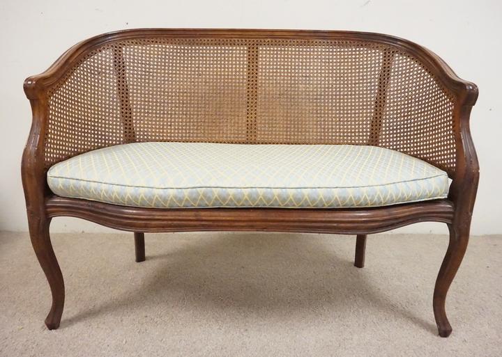 CARVED SETTEE: CARVED SETTEE WITH A WICKER SEAT AND BACK. 45 INCHES WIDE. 34 INCHES HIGH.