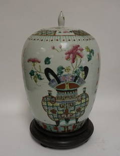 HAND PAINTED ASIAN JAR: HAND PAINTED ASIAN COVERED JAR DECORATED WITH URNS OF FLOWERS AND CALLIGRAPHY. SLIVER OFF THE FINIAL OF THE LID. HAS A WOODEN BASE. TOTAL HEIGHT 14 1/2 IN