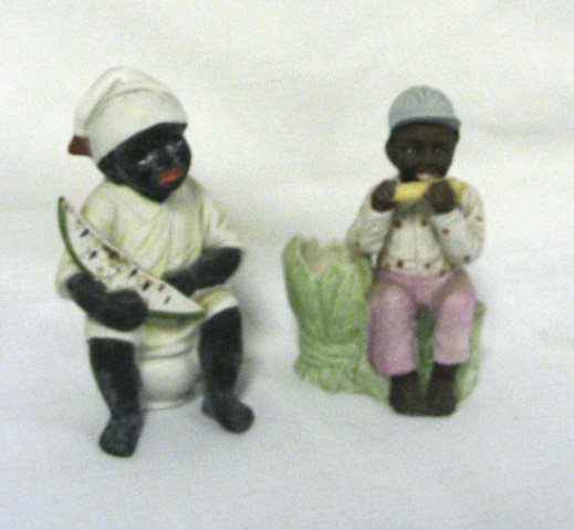 2 BISQUE FIGURES OF BLACK CHILDREN; ONE IS ON A C: 2 BISQUE FIGURES OF BLACK CHILDREN; ONE IS ON A CHAMBER POT HOLDING A SLICE OF WATERMELON (HAIRLINE) 4 3/4 IN H & THE OTHER IS A MATCH HOLDER WITH BOY EATING AN EAR OF CORN; SMALL NICK ON THE FOOT; 4