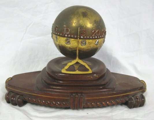 CLOCK; BRASS SPHERICAL DIAL MOUNTED ON A WOODEN B