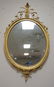 DECORATIVE ARTS IN ORNATE OVAL GILT MIRROR