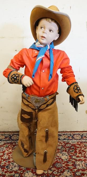 YOUNG BOY MANNEQUIN CLOTHED WITH VINTAGE LEVI RED TAB: YOUNG BOY MANNEQUIN CLOTHED WITH VINTAGE LEVI RED TAB JEANS, DECORATED CHAPS, DECORATED FRINGED CUFFS, LEATHER BELT WITH BUCKLE, BANDANNA, VINTAGE SEARS WESTERN SHIRT AND FELT HAT WITH FEATHER. MANNEQ
