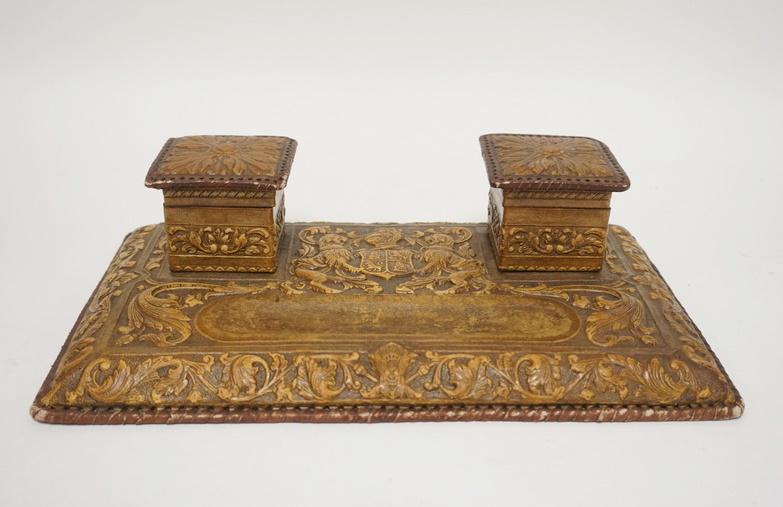 DOUBLE INKWELL W/ EMBOSSED LEATHER COVER: DOUBLE INKWELL W/ EMBOSSED LEATHER COVER, HAS A COAT OF ARMS & RAMPANT LIONS ONE INSET IS MISSING. 13 3/4 IN X 7 3/4 IN