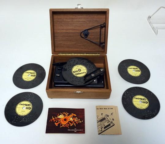 THORENS REUGE MUSIC BOX: THORENS REUGE MUSIC BOX WITH 4 EXTRA DISCS, IN WALNUT BOX. APPROXIMATELY 7 1/2 IN X 6 IN X 3 1/2 IN