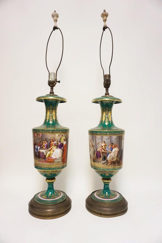 PAIR OF PORCELAIN HAND PAINTED URN LAMPS: PAIR OF PORCELAIN HAND PAINTED URN LAMPS DEPICTING BANQUET SCENES W/GILT TRIM ACCENTS, APPROXIMATELY 21 IN HIGH BEFORE HARP, APPEARS TO BE SEPARATE AT BASE STEMS