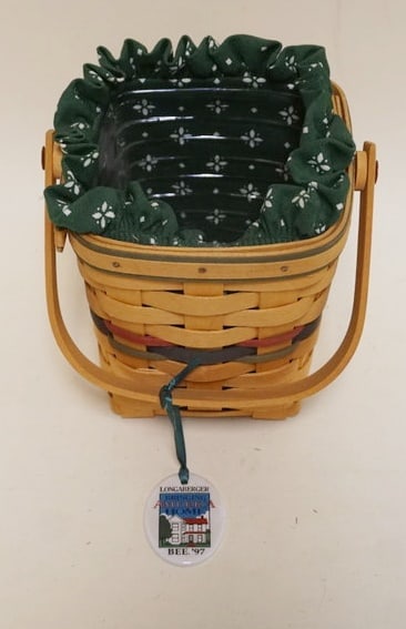 1997 BRINGING AMERICA HOME BEE BASKET SIGNED: 1997 BRINGING AMERICA HOME BEE BASKET WITH LINER, PROTECTOR AND HANG TIE. SIGNED BY GINNY AND JERRY. APPROXIMATELY 5 1/2 IN SQ X 6 IN H