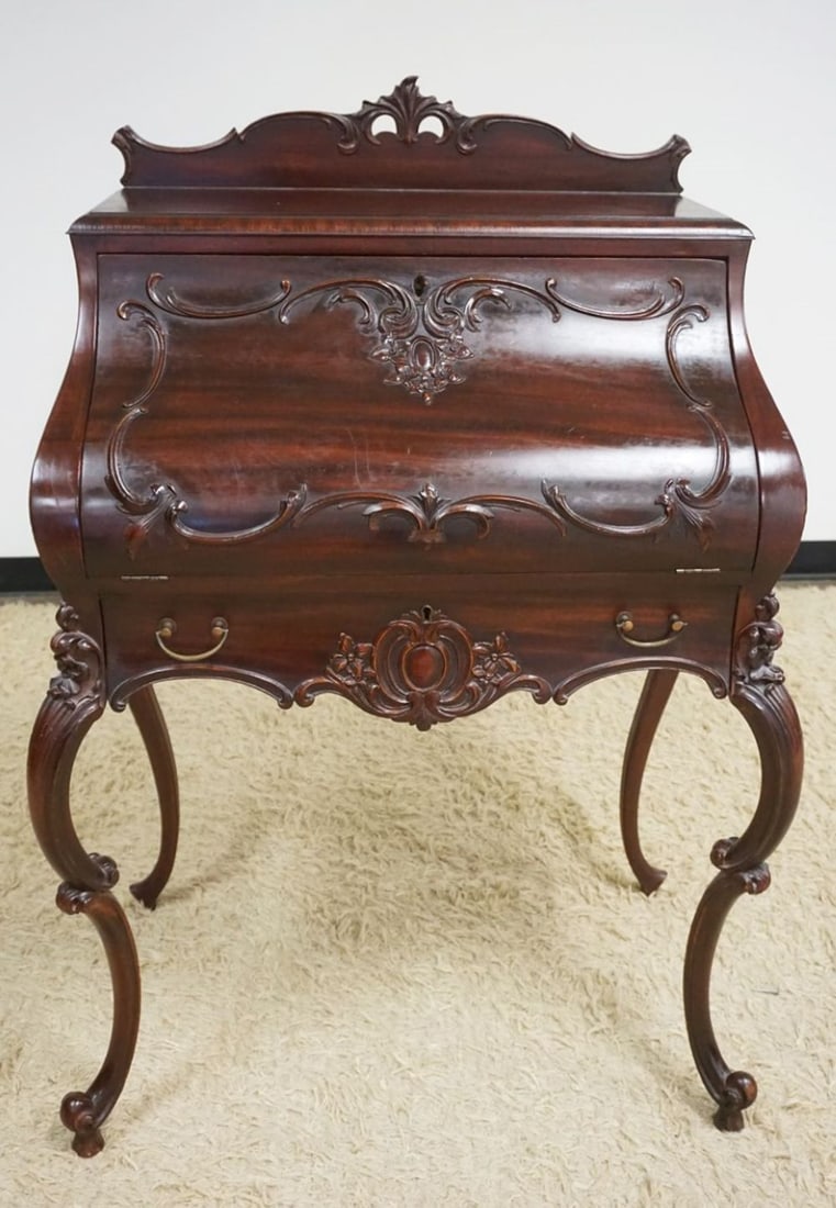 ORNATE MAHOGANY BOMBE STYLE DESK: ORNATE MAHOGANY BOMBE STYLE DESK W/CARVED CABRIOLE LEGS & APPLIED CARVINGS, SOME LOSS, APPROXIMATELY 30 IN X 20 IN X 48 IN HIGH