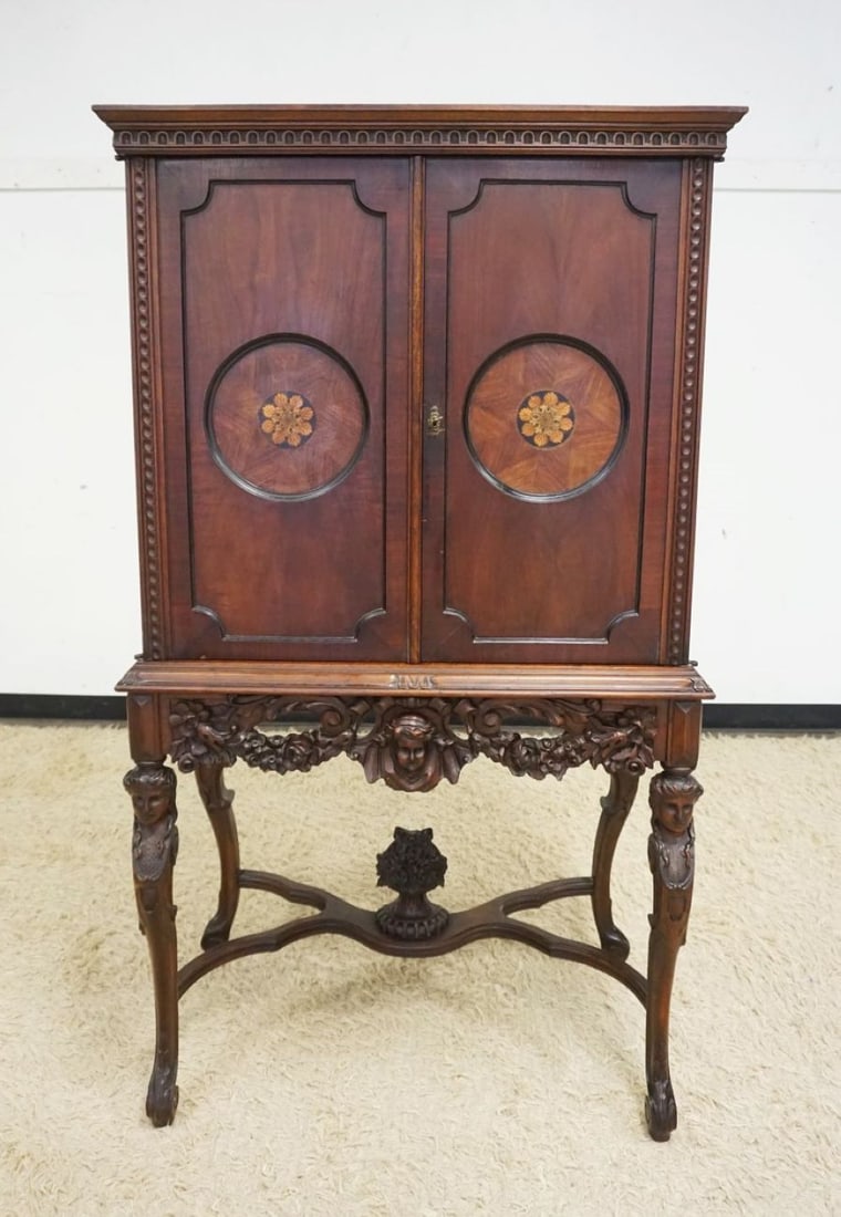 OUTSTANDING WALNUT CARVED 2 DOOR CABINET: OUTSTANDING WALNUT CARVED 2 DOOR CABINET, DOORS HAS 2 ROUND INLAID PANELS, INTERIOR W/3 SHELVES & ONE DRAWER, BASE HAS CARVING OF WOMAN BUST ON ALL FOUR LEGS ALONG W/A CHERUB & FLOWER BASKET AT CENTER