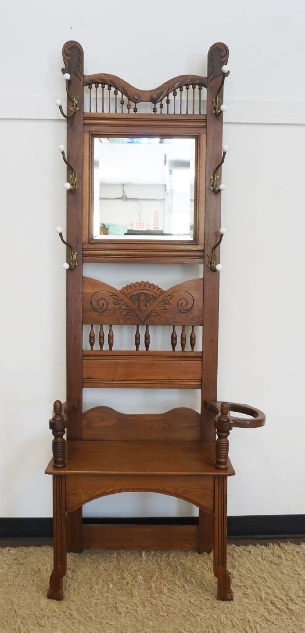 CARVED WALNUT VICTORIAN HALL RACK: CARVED WALNUT VICTORIAN HALL RACK WITH BRASS COAT & HAT HANGERS, TURNED SPINDLE GALLERY AND CENTER, APPROXIMATELY 32 IN X 15 IN X 81 IN H