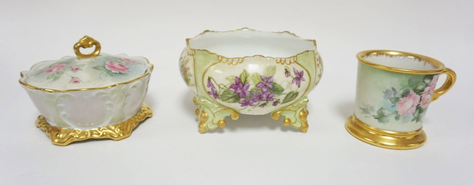 HAND PAINTED LIMOGES FOOTED BOWL, ETC: HAND PAINTED LIMOGES FOOTED BOWL, SHAVING MUG & UNMARKED COVERED DISH, FOOTED BOWL HAS IMAGES OF DIFFERENT FLORAL ARRANGMENTS ALL AROUND W/GILT TRIM, APPROXIMATELY 8 IN X 5 IN HIGH
