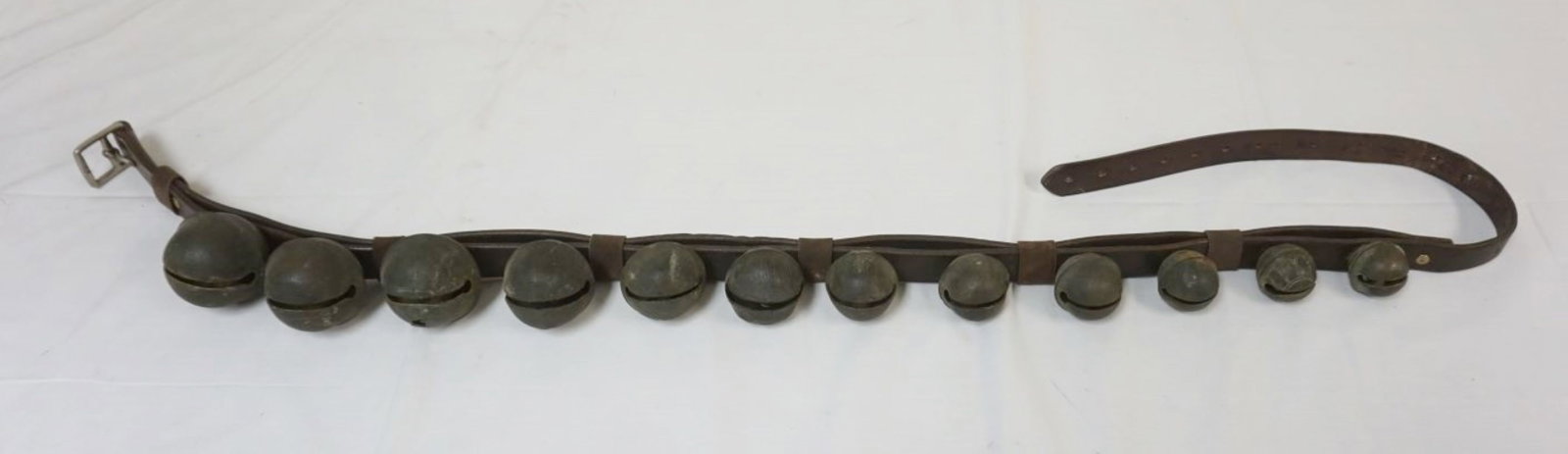 BRASS SLEIGH BELLS: BRASS SLEIGH BELLS, 12 MOUNTED ON LEATHER STRAP, LARGEST APPROXIMATELY 3 IN