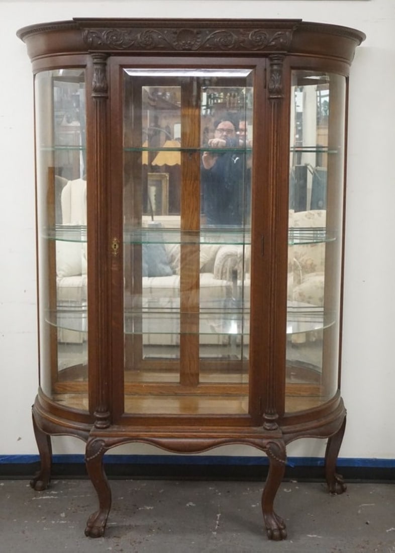 ORNATE OAK CHINA CABINET: ORNATE OAK CHINA CABINET WITH BEVELED GLASS DOOR AND CURVED SIDES, HAVING A SHELL CARVED CREST AND REEDED COLUMN SIDES ON BALL AND CLAW FEET, APPROXIMATELY 52 IN X 18 IN X 71 IN H