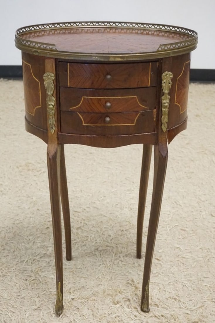 FRENCH INLAID OVAL STAND: FRENCH INLAID 3 DRAWER OVAL STAND WITH METAL MOUNTS AND BRASS GALLERY TOP, SOME VENEER LOSS, APPROXIMATELY 17 IN X 13 IN X 29 IN H