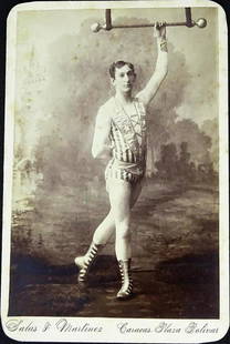 1890'S TRAPEZE ARTIST CABINET CARD: VENENZUELAN ARTIST IN PATRIOTIC ATTIRE POSING WITH FLYBAR.