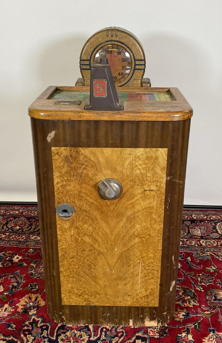 JENNINGS BOBTAIL NICKEL SLOT MACHINE: 1941. HAVING TOTALIZER, GLASS TOP DISPLAY AND WOODEN CABINET. LIGHTS UP BUT DOESN'T PLAY. THERE IS A CUT-OUT IN THE LOWER PORTION OF THE LEFT-SIDE OF THE CABINET. THE ACTION HANDLE ON THE FRONT IS BRO
