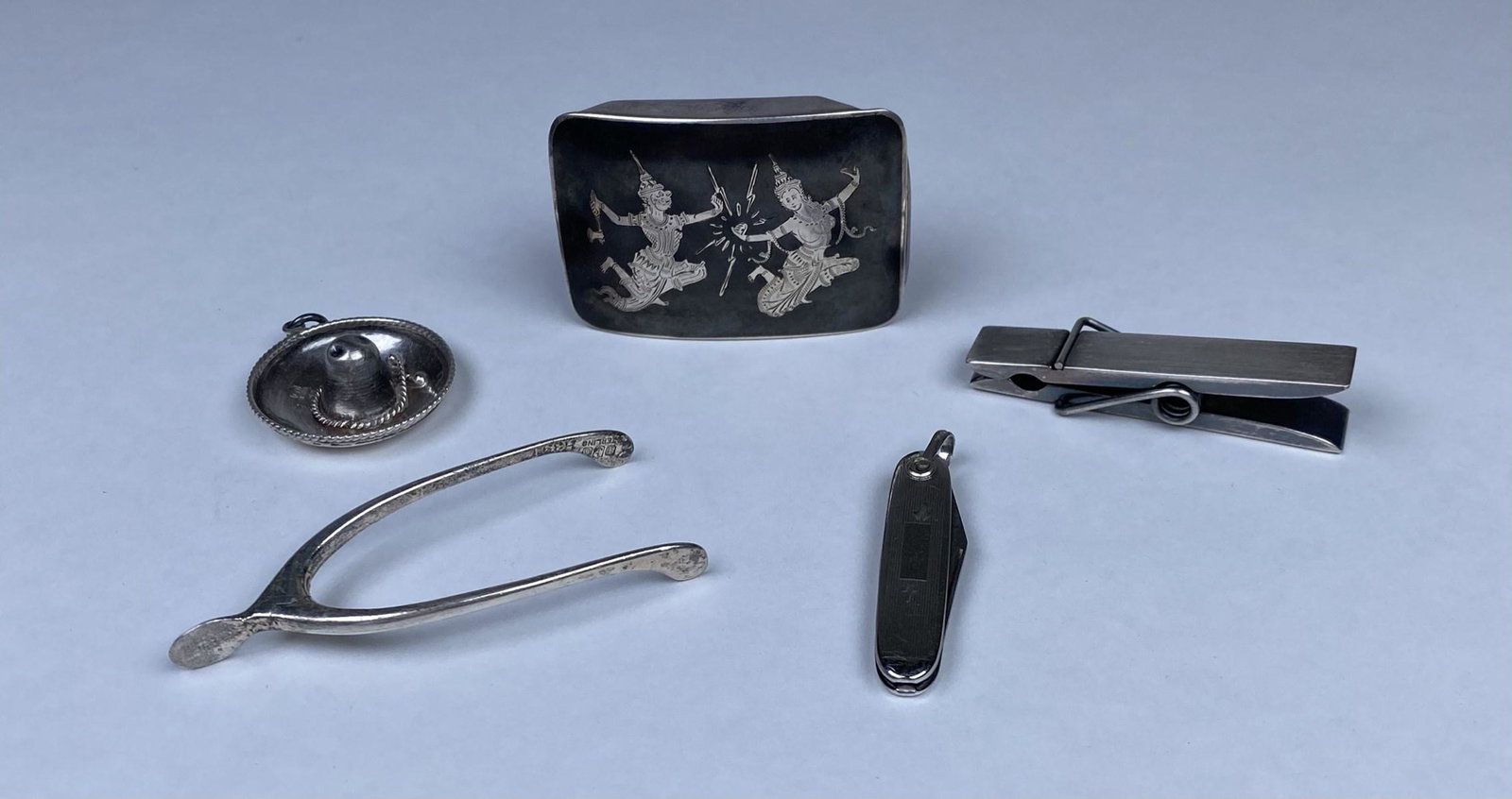 GROUPING OF STERLING SILVER ITEMS: BUCKLE, CLOTHES PIN PAPER WEIGHT, WISHBONE KNIFE REST, SOMBRERO CHARM, PEN KNIFE. 69 GRAMS TOTAL WEIGHT