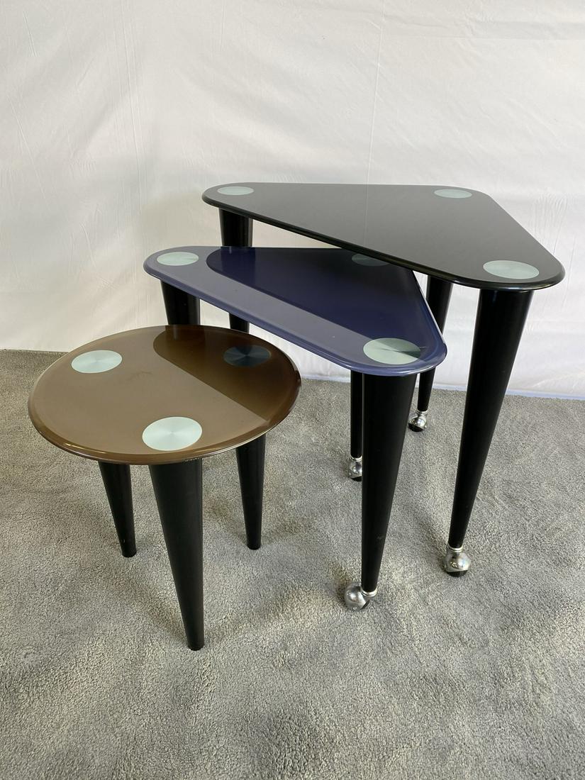 MODERN NEST OF TABLES: WHEELED, WITH TAPERED LEGS. GLASS TOP FINISH WITH CORNER ACCENTS. LARGEST IS 27"X27"X27"