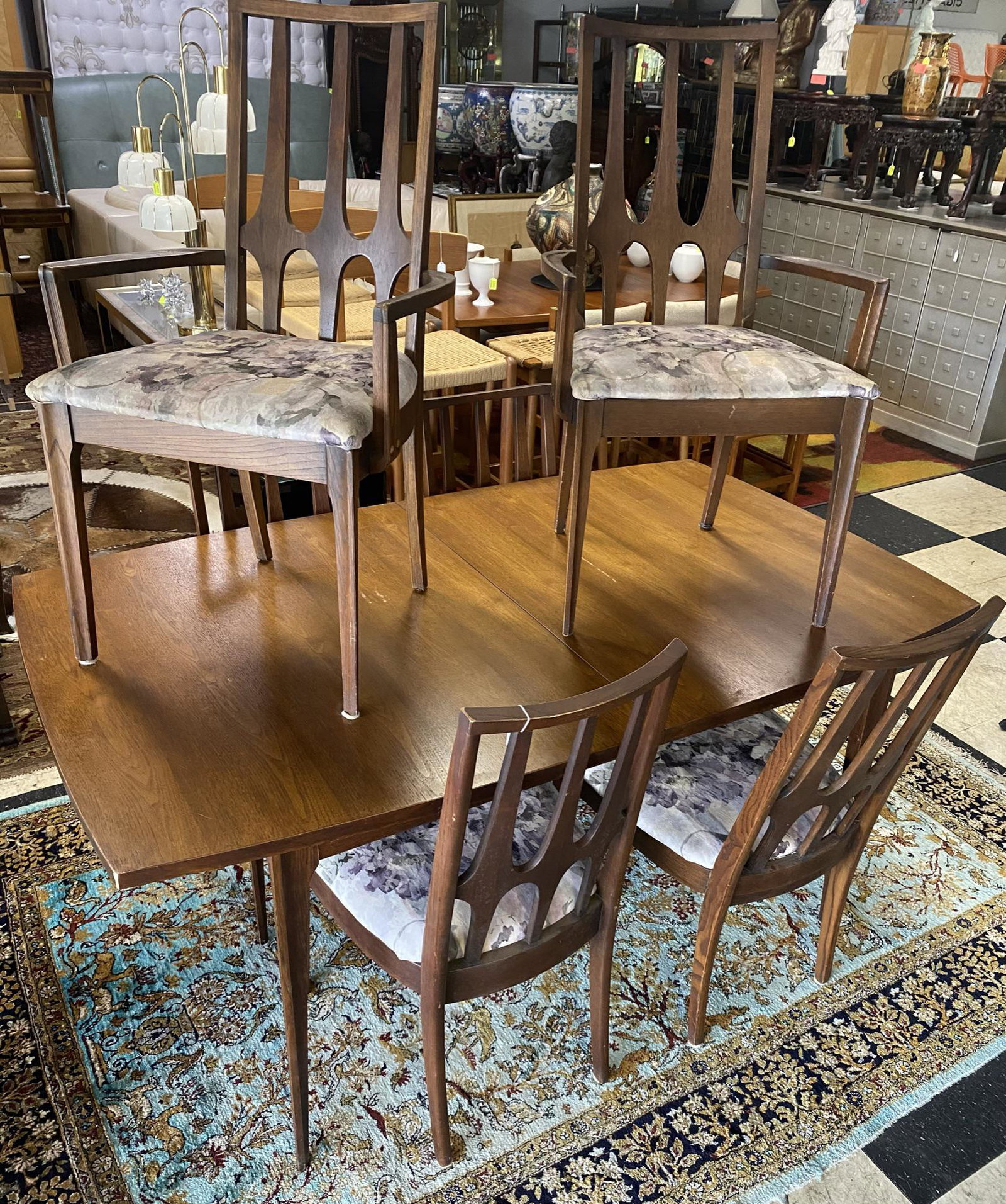 BROYHILL BRASILIA DINETTE: HAVING TABLE AND 6 CHAIRS. WEAR CONSISTENT WITH AGE. SOME SCUFFS TO WOOD SURFACE BUT NO GOUGES. ONE CHAIR IS LOOSE AT SEAT/LEG JOINT.