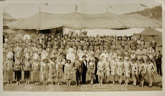 EDWARD J. KELTY (AMERICAN, 20TH C.) PHOTOGRAPH: ORIGINAL KELTY PHOTOGRAPH OF SELLS FLOTO CIRCUS, WATERBURY, CONNECTICUT, 1928. CIRCUS CAST AND CREW WITH BIG TOP IN THE BACK GROUND. 12"X20", RUBBER STAMP ON VERSO.