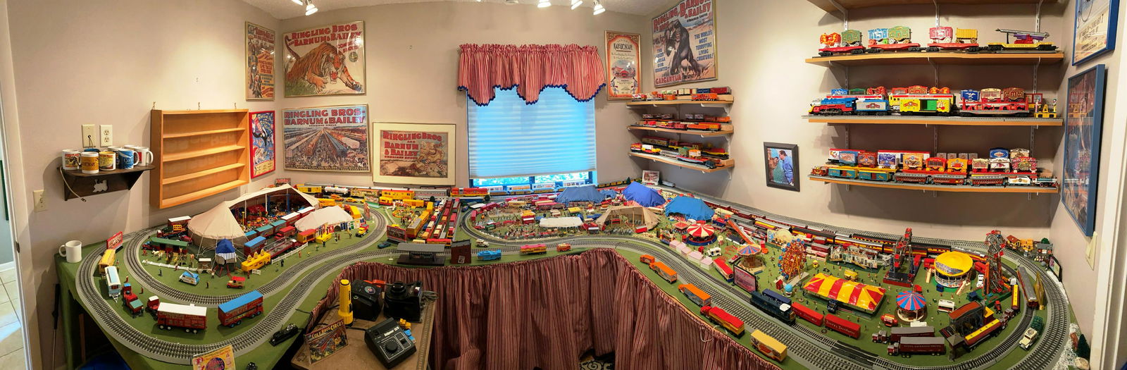 FATHER JERRY HOGAN CIRCUS MODEL LAYOUT: 92 SQUARE FOOT LAYOUT LOCATED IN THE RESIDENCE OF FATHER JERRY HOGAN. HAND-BUILT LAYOUT WITH MULTIPLE SCALE OF TRAINS, BIG TOP, TRAINYARD, CARNIVAL, CONTROLLERS AND SURPLUS OF TRAINS AS SHOWN ON WALL
