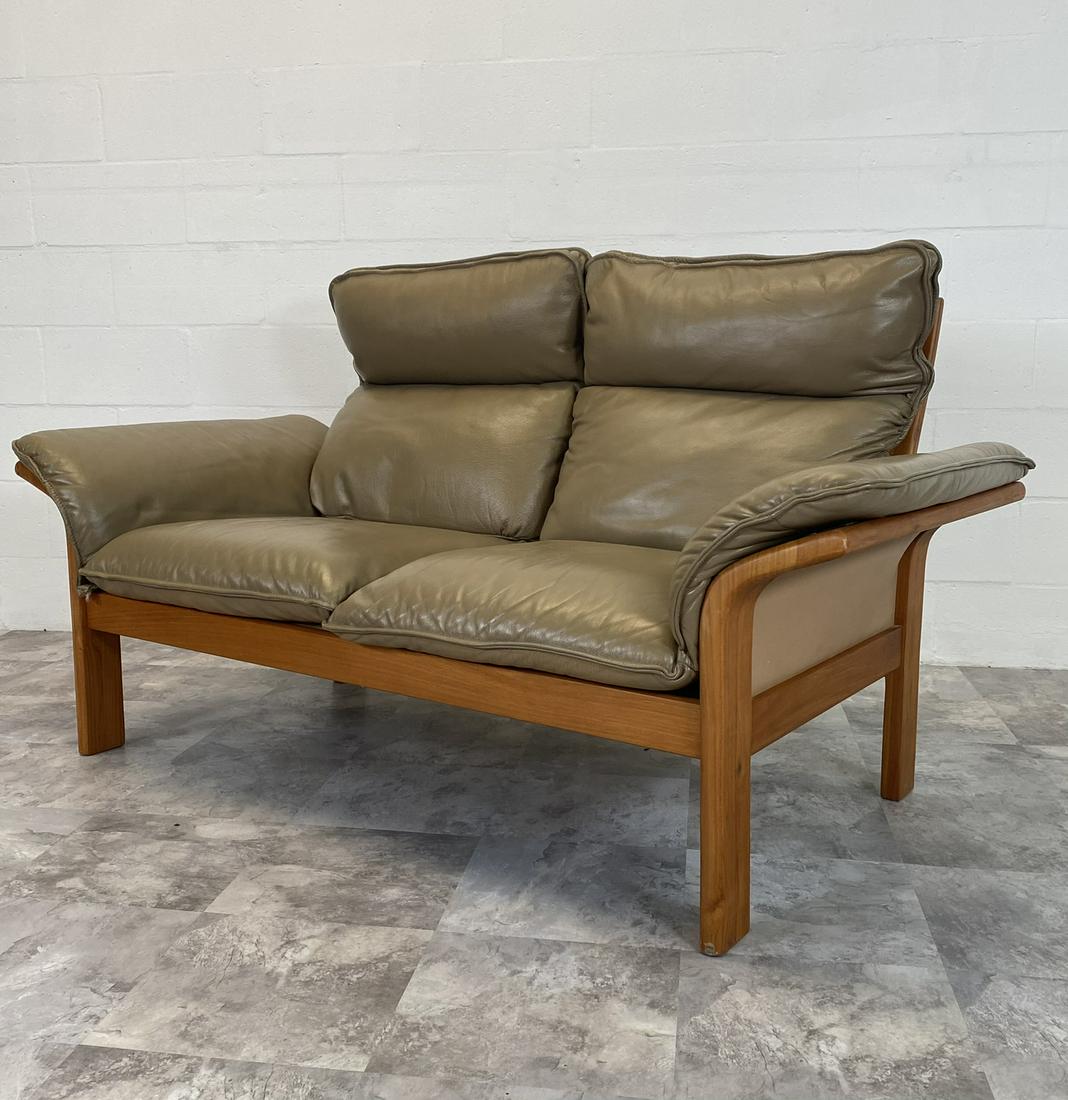 DANISH TEAK AND LEATHER LOVE SEAT: TEAK STRUCTURE WITH BROWN LEATHER SEATING AND ARMS.W. 62 in H. 34 in D. 30 in SEAT H. 15 in